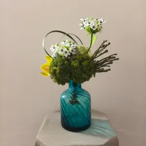 Modern artificial flower bouquet with teal glass vase for home decor, photography prop interior.