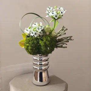 Modern silver metallic vase with artificial flower bouquet for home interior decor.