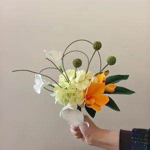 Vue détaillée du bouquet de fleurs artificielles noué à la main, aux éléments floraux colorés.
