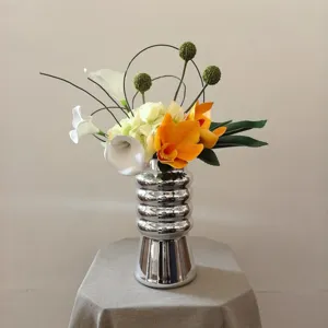 Bouquet de fleurs artificielles créatif avec vase argenté strié pour décoration intérieure.