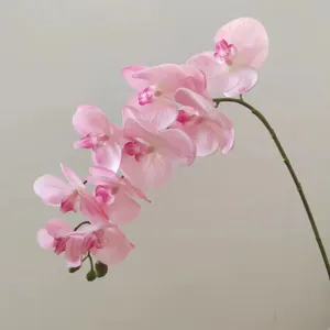 Primo piano di un ramo di orchidea phalaenopsis artificiale rosa con nove teste di fiori realistiche.
