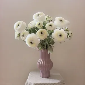 Bouquet di ranuncoli bianchi artificiali con vaso in ceramica rosa per decorazione.