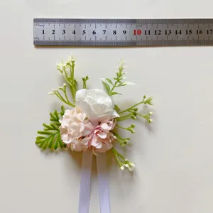 Nahaufnahme der künstlichen rosa und weißen Blumen Korsage mit grünen Blättern und Band.