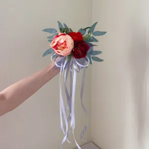 Artificial flower bouquet with ribbons, wedding chair back decor, elegant floral arrangement.