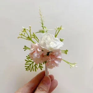 Nahaufnahme eines künstlichen rosa-weißen Ansteckblumen mit grünen Blättern für die Hochzeit.
