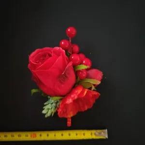 Red artificial rose boutonniere with berries for wedding groom and business suit decoration.