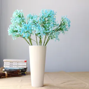 Fiori artificiali di gipsofila blu in vaso di ceramica bianca per decorazione casa e fotografia.