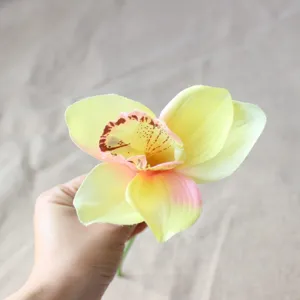 Hand-held artificial silk orchid flower head detail, faux cymbidium for home decor crafts.