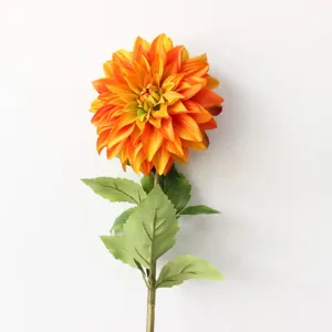 Detailed view of a single large orange artificial dahlia flower with realistic green leaves and stem.