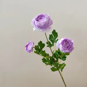 Close-up detail of purple artificial ranunculus flower branch with green leaves and stem.
