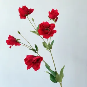 Primo piano dettagliato di un ramo di anemone artificiale rosso con foglie verdi.