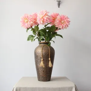 Detail close-up shot of artificial pink dahlia flowers bouquet in a vintage textured vase.