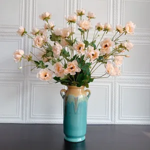 Vista dettagliata di un elegante allestimento di fiori artificiali di pesco in vaso di ceramica.