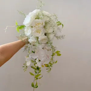 Gros plan détaillé d'un bouquet de mariée artificiel en cascade avec roses et orchidées.
