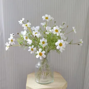 Detailed view of white artificial cosmos flower bouquet in clear glass vase for home decor setup.