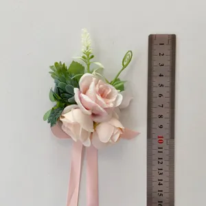 Detailed shot of pink artificial rose boutonniere with green leaves and ribbon for wedding.