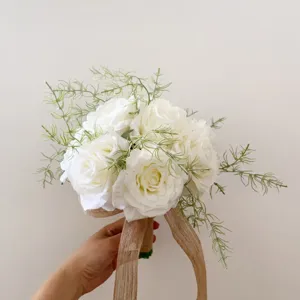 Détails du bouquet de roses artificielles blanches avec feuillage vert et ruban de jute.