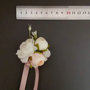 Artificial flower corsage detail shot, featuring soft pink and white peonies with ribbon.