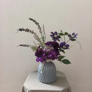 Bouquet de fleurs artificielles violettes dans un vase en céramique grise déco.