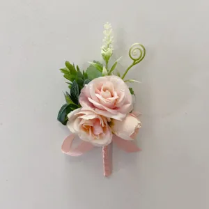Pink artificial rose boutonniere detail shot, elegant wedding floral accessory for bride.