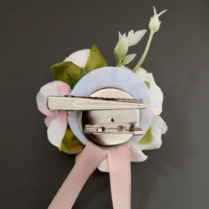 Back detail of artificial floral hair clip corsage, pink and white fabric flower with metal pin.