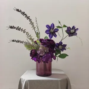 Bouquet de fleurs de clématites artificielles violettes avec vase en verre, déco et accessoire photo.