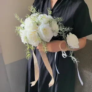 Détail de bouquet de mariée de roses artificielles blanches avec herbe verte et ruban de jute.