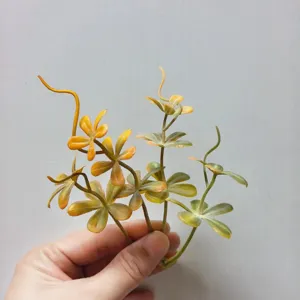 Close-up detail of 5-petal artificial PVC green leaves for DIY corsage and hat decoration.