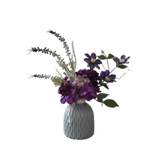 Bouquet de fleurs artificielles violettes dans un vase texturé gris pour décoration.