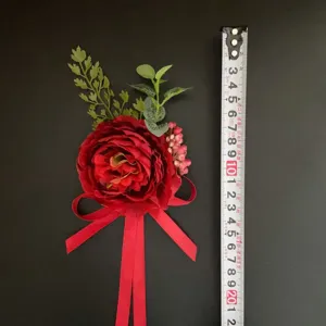 Red artificial flower boutonniere wrist corsage for wedding groom bridesmaid photography detail.