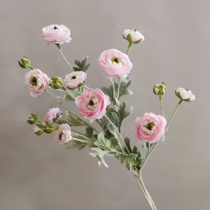 Detailaufnahme künstlicher rosa Ranunkeln Zweig mit realistischer Textur und grünen Blättern.