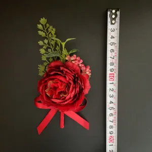 Detail view of red artificial rose boutonniere and green leaves for wedding decor.