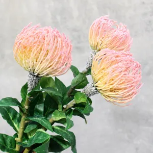 Artificial pincushion flower branch with three pink-yellow flower blooms and realistic green leaves.