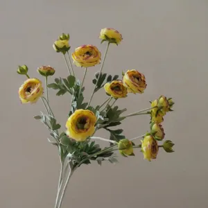 Nahaufnahme Detail eines künstlichen gelben Ranunkeln Seidenblumenstraußes mit Blättern.