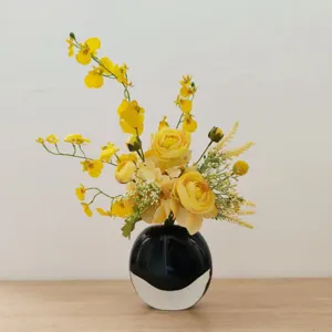 Vue détaillée de l'arrangement floral artificiel jaune dans un vase noir pour table.