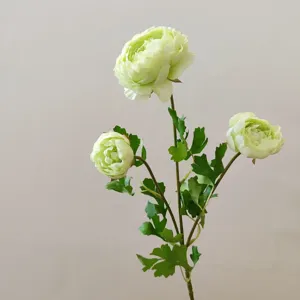 Close-up detail of artificial green ranunculus flower branch with realistic leaves and stems.
