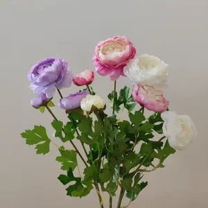 Detailed view of colorful artificial ranunculus flowers bouquet with green leaves.