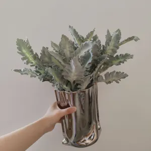 Artificial silver ragwort plant in a shiny metallic vase for home decor and floral arrangement.