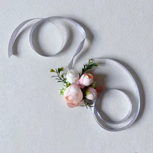 Artificial pink flower corsage with grey ribbon, elegant wedding wrist flower detail view.