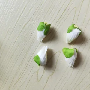 Close-up details of four artificial white poppy flower buds with green sepals for DIY crafts.