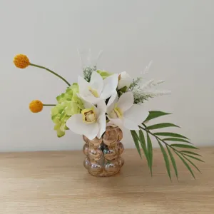 Détails de l'arrangement floral artificiel blanc et vert avec vase en verre pour décor.