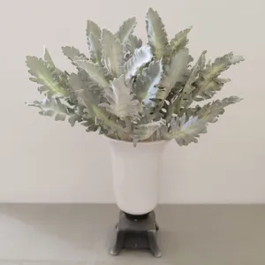 Detail shot of flocked artificial dusty miller silver leaf plant in white ceramic vase.