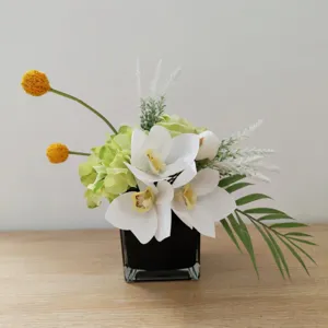 Arrangement de fleurs artificielles blanches et vertes dans un pot carré noir moderne