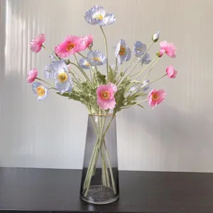 Artificial poppy flower bouquet detail shot with pink and blue blossoms in a modern glass vase.