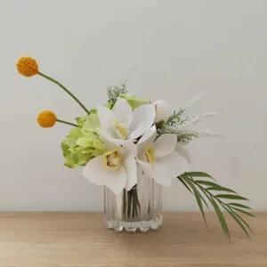 Gros plan de la composition florale artificielle blanche et verte en vase en verre.