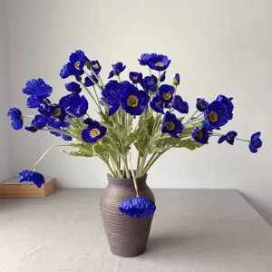 Detailed view of artificial blue poppy flower bouquet in a textured ceramic vase for decor.