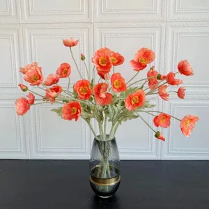 Close-up detail of coral pink artificial poppy flower bouquet in glass vase, elegant soft home decor.