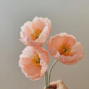 Primo piano dettagliato di fiori di papavero artificiali pesca con steli floccati e stami gialli.