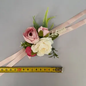 Detailed view of handmade artificial rose wrist corsage with ribbon for wedding and party.