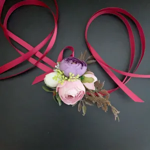 Vista detallada de un corsé de flores artificiales con rosas rosas y cintas rojas de seda.